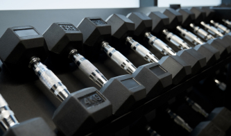 Close up of black dumbbells different weight on shelf in modern gym. Concept of special sports equipment for exercise and for improving body.